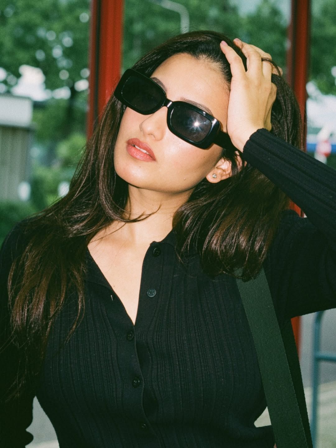 Creator Deepika Pilli wearing a stylish black outfit and oversized sunglasses  posing confidently in a modern urban setting