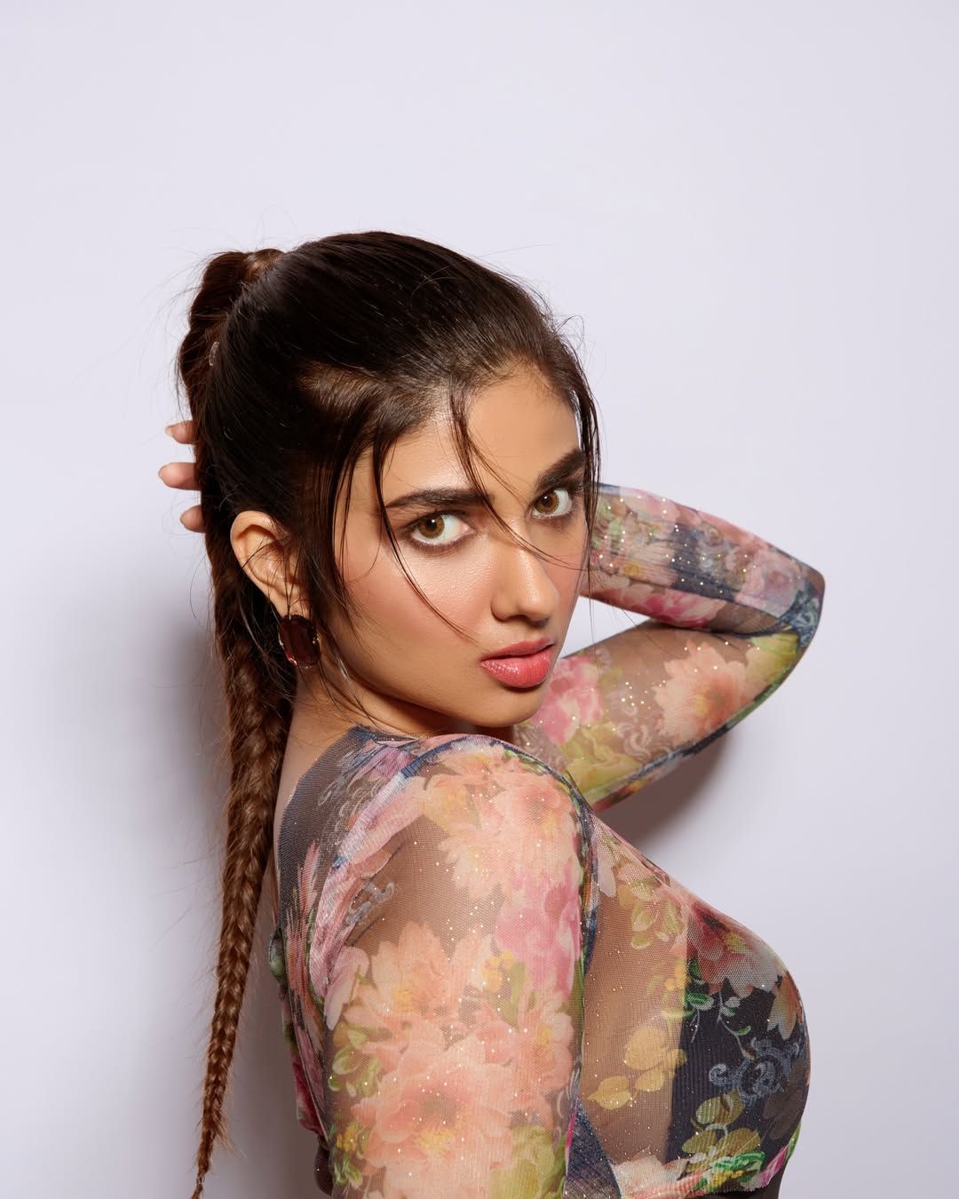 Creator Pragya Nagra wearing a stylish floral mesh outfit with braided hair, posing in a modern fashion portrait setup
