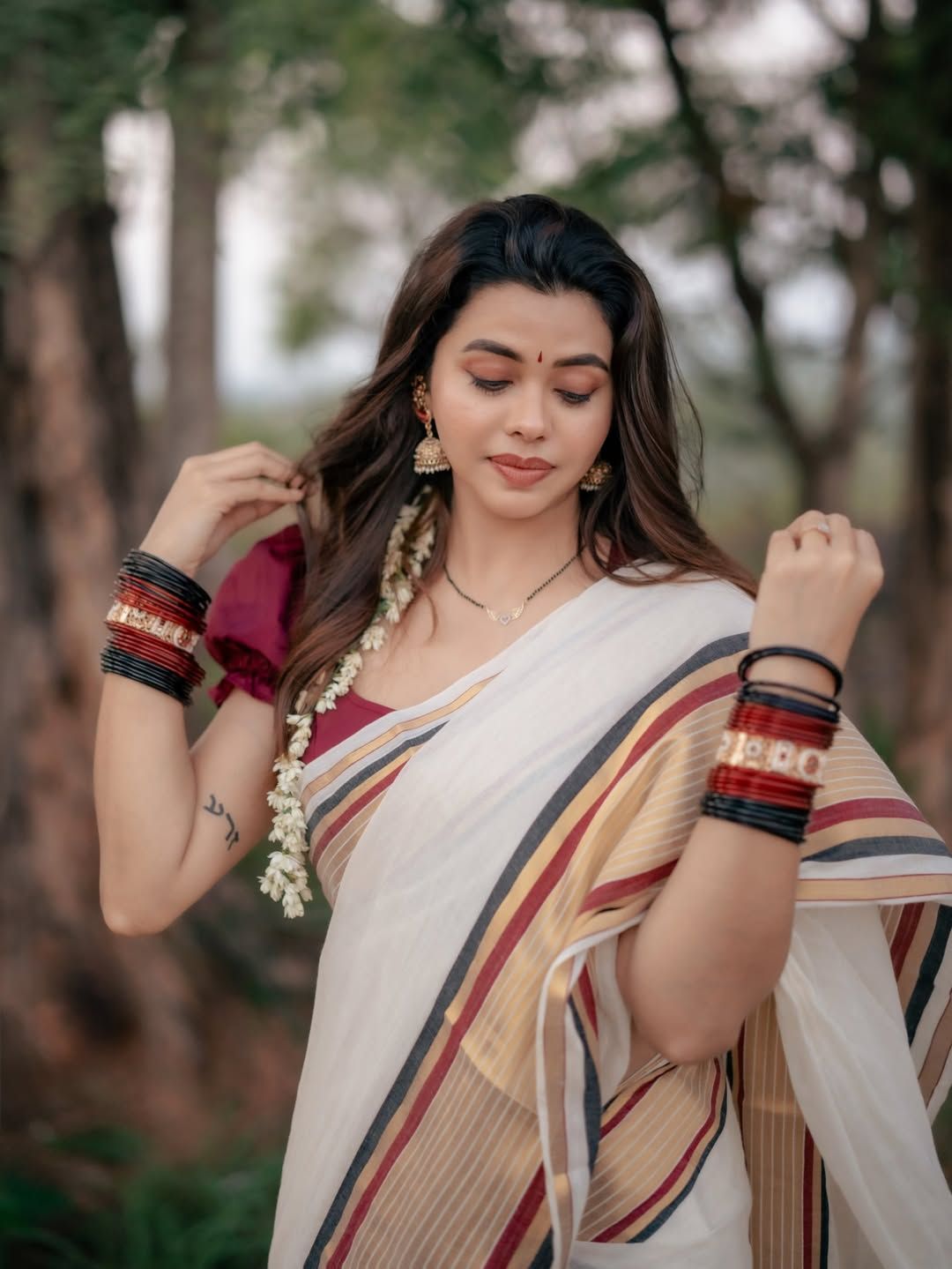 Creator Tashya wearing a traditional Kerala saree with classic jewelry and jasmine flowers, posing gracefully outdoors