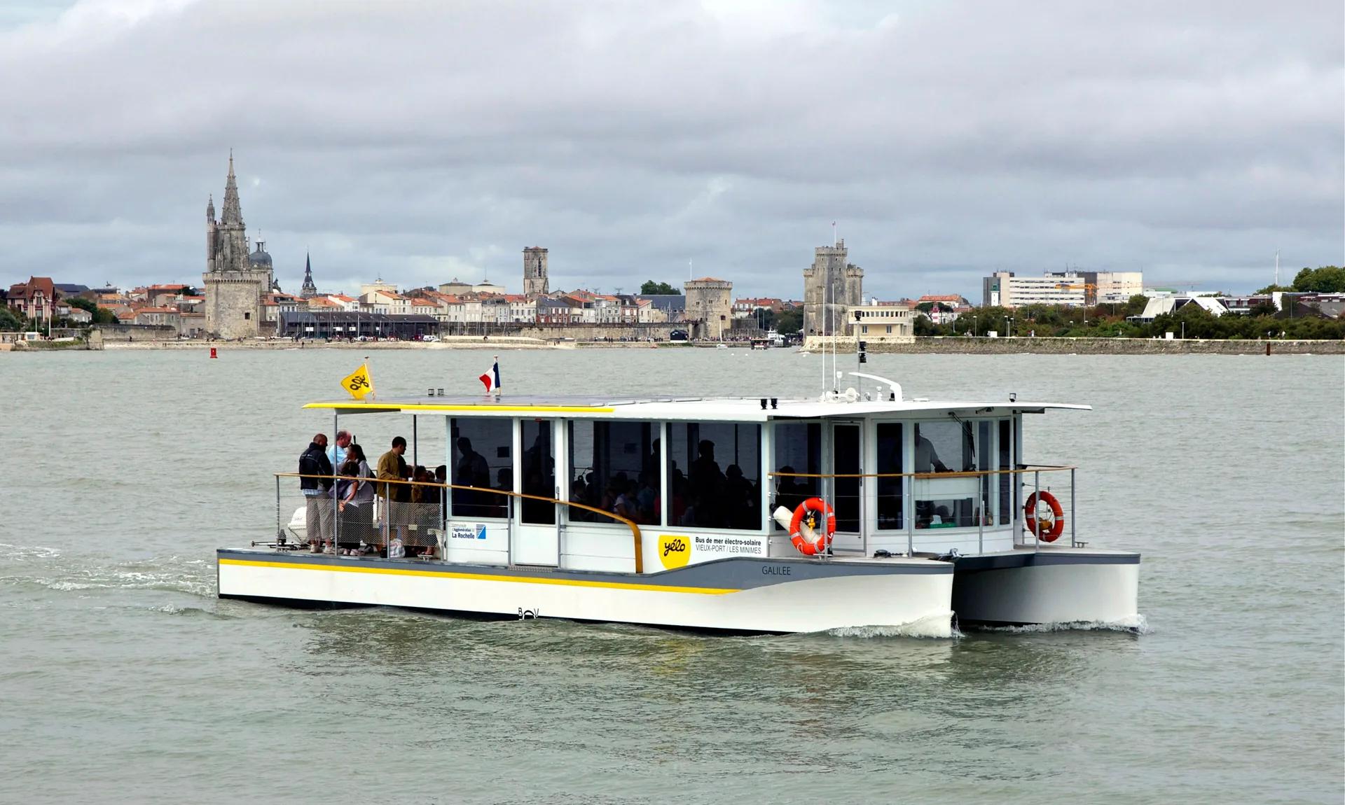 Le bus de mer de La Rochelle traversant le port, les tours du Vieux-Port derrière.