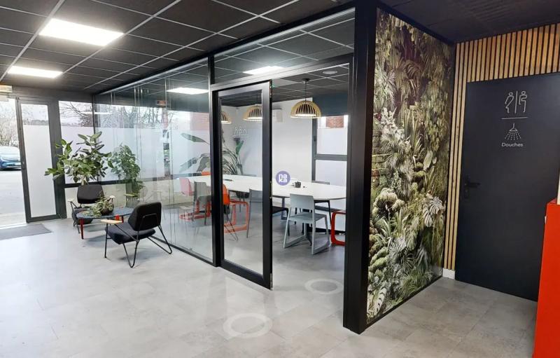 Office lobby with a glass-walled meeting room and a green wall