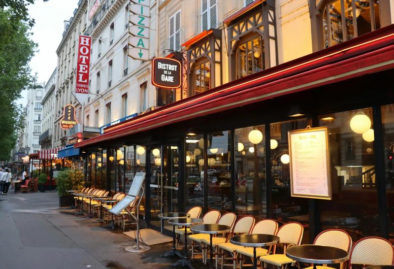 Terrace of a Paris bistro, with cane chairs lined up under the red awning