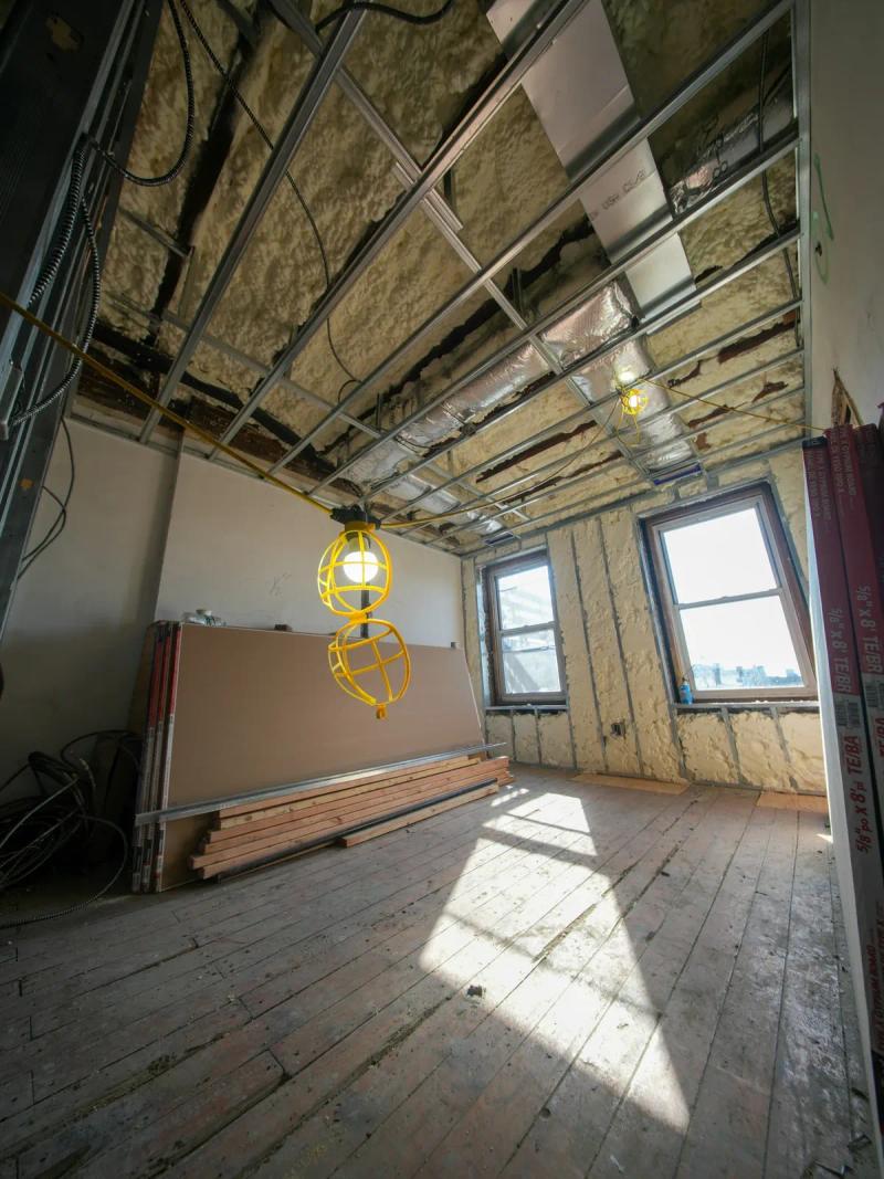 Room under renovation beneath an insulated ceiling, with metal framing and old parquet flooring