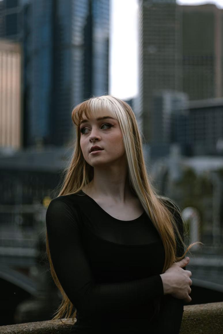 A young adult standing thoughtfully, Melbourne skyline behind