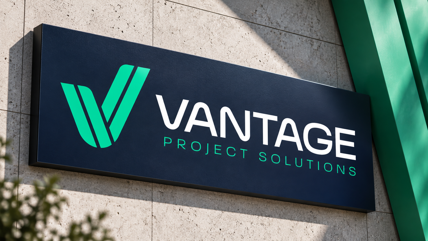Vantage Project Solutions logo with a green V-shaped check mark and white lettering on a navy sign mounted on a concrete wall.