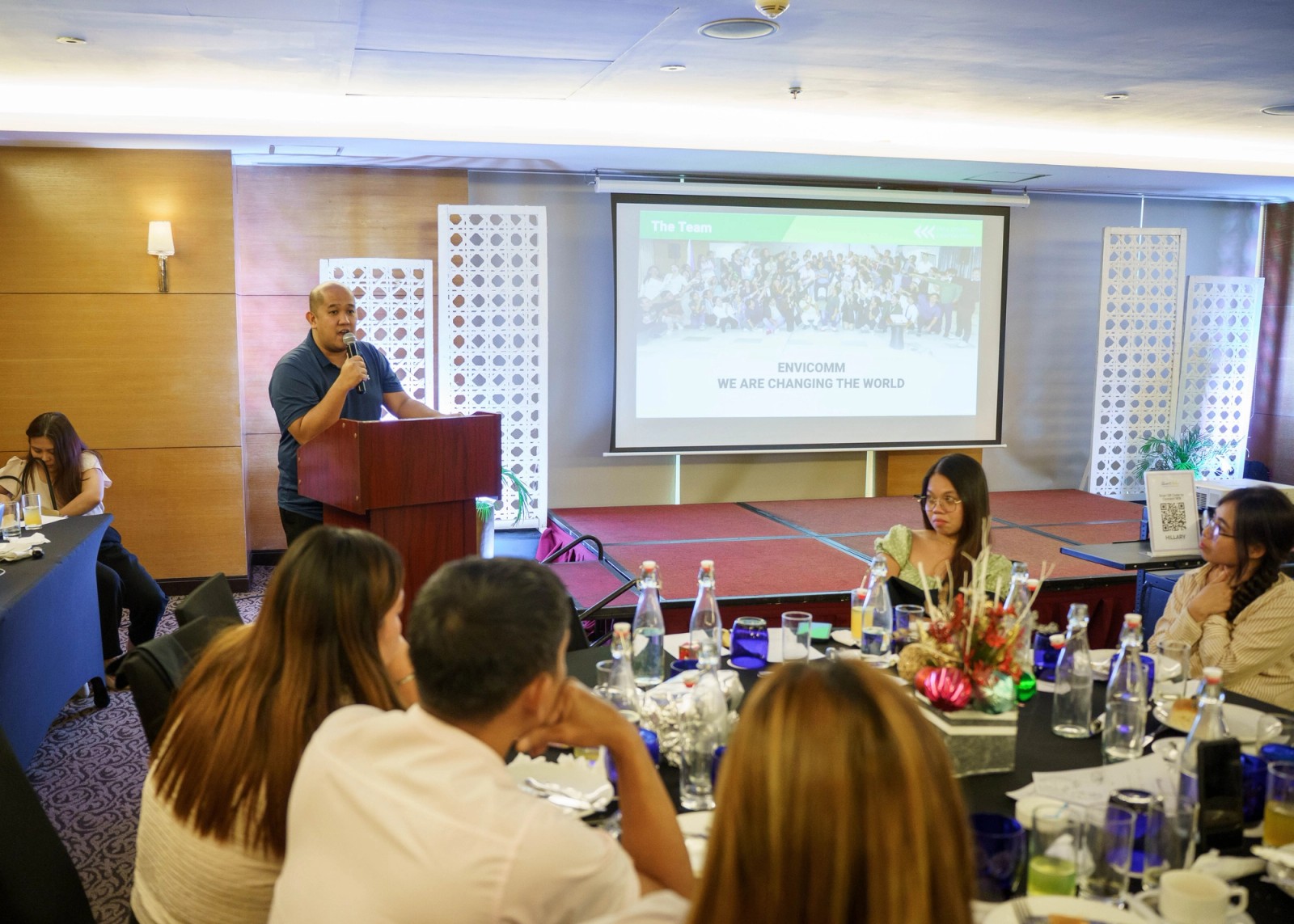 A speaker addressing seated guests at a company presentation