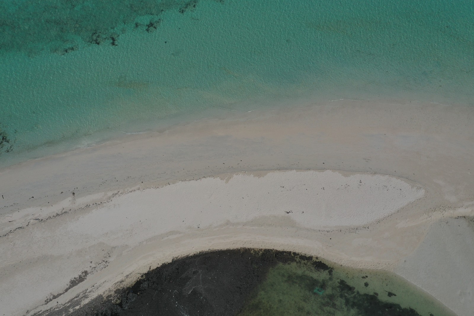 Aerial view of a white sandbar meeting clear turquoise water
