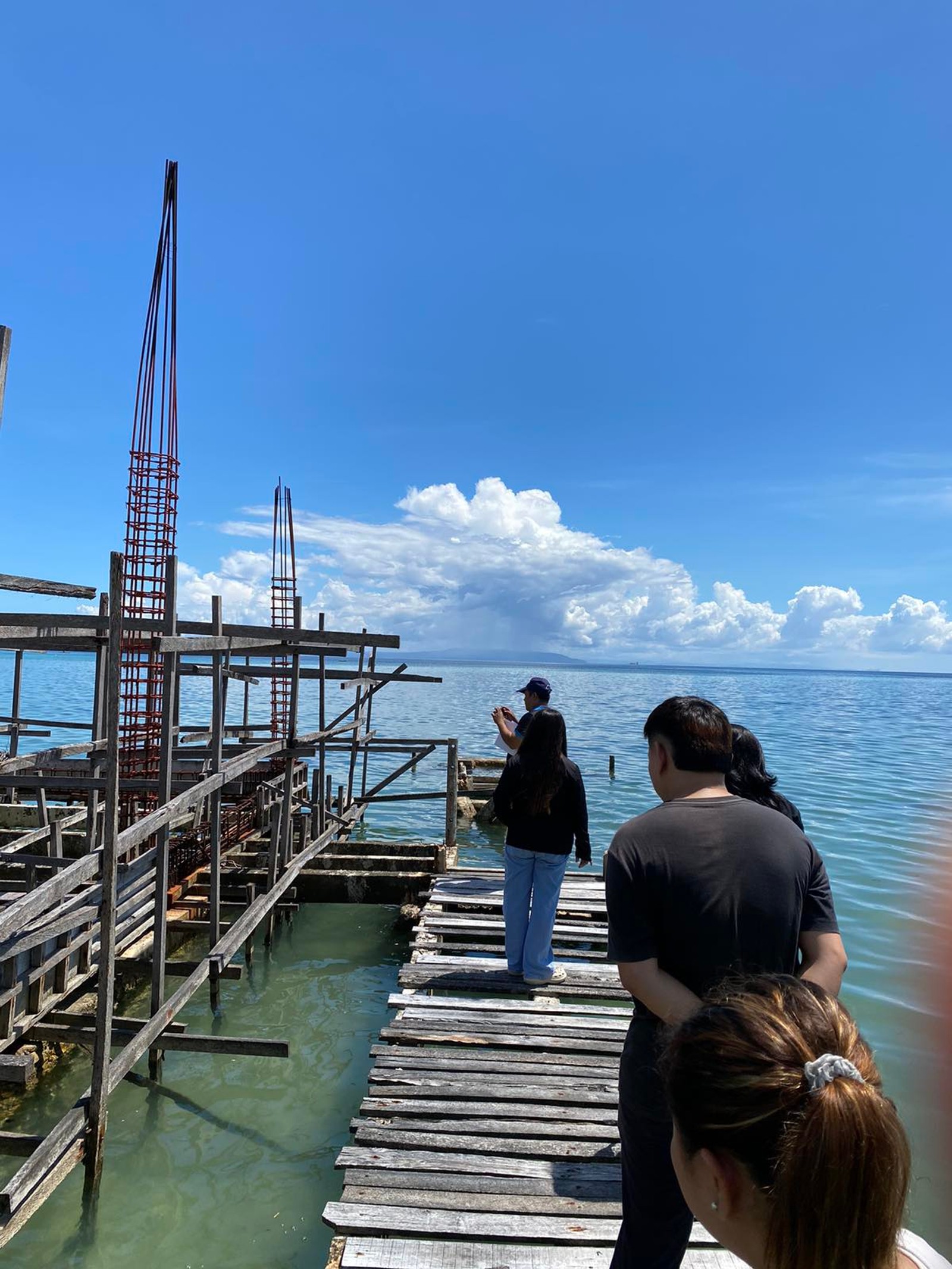 A field team inspecting a timber pier under construction over shallow water