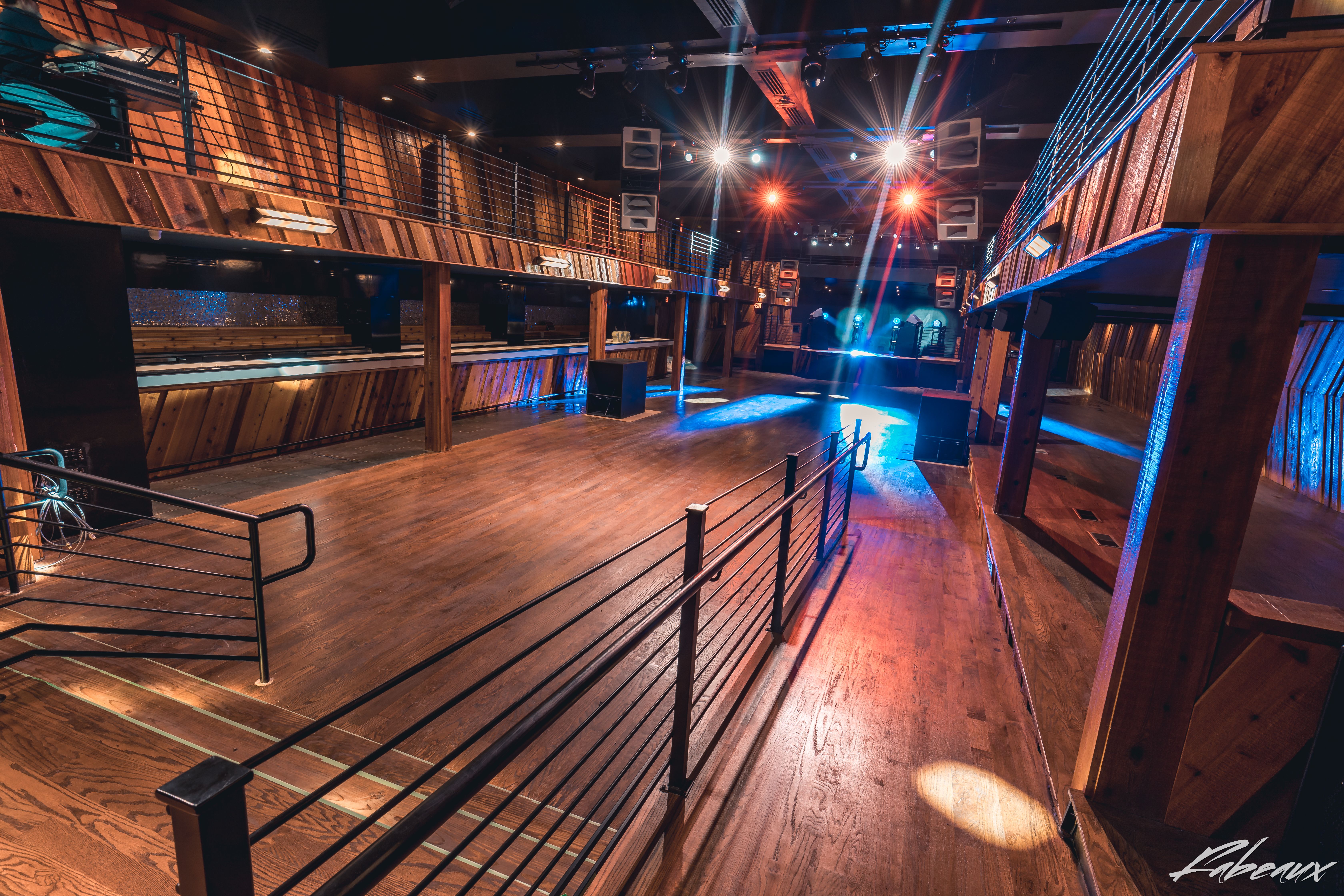 Wide Back of House shot of Ravine showcasing the wooden floors, black railing, balconies, production, and bars.