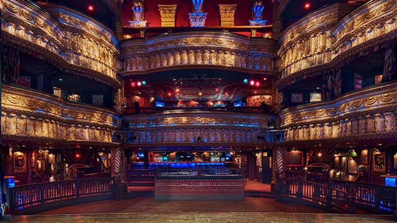 Empty wide shot of House of Blues from the stage point of view. Blue light illuminates the bars and balconies. The floor is wooden.