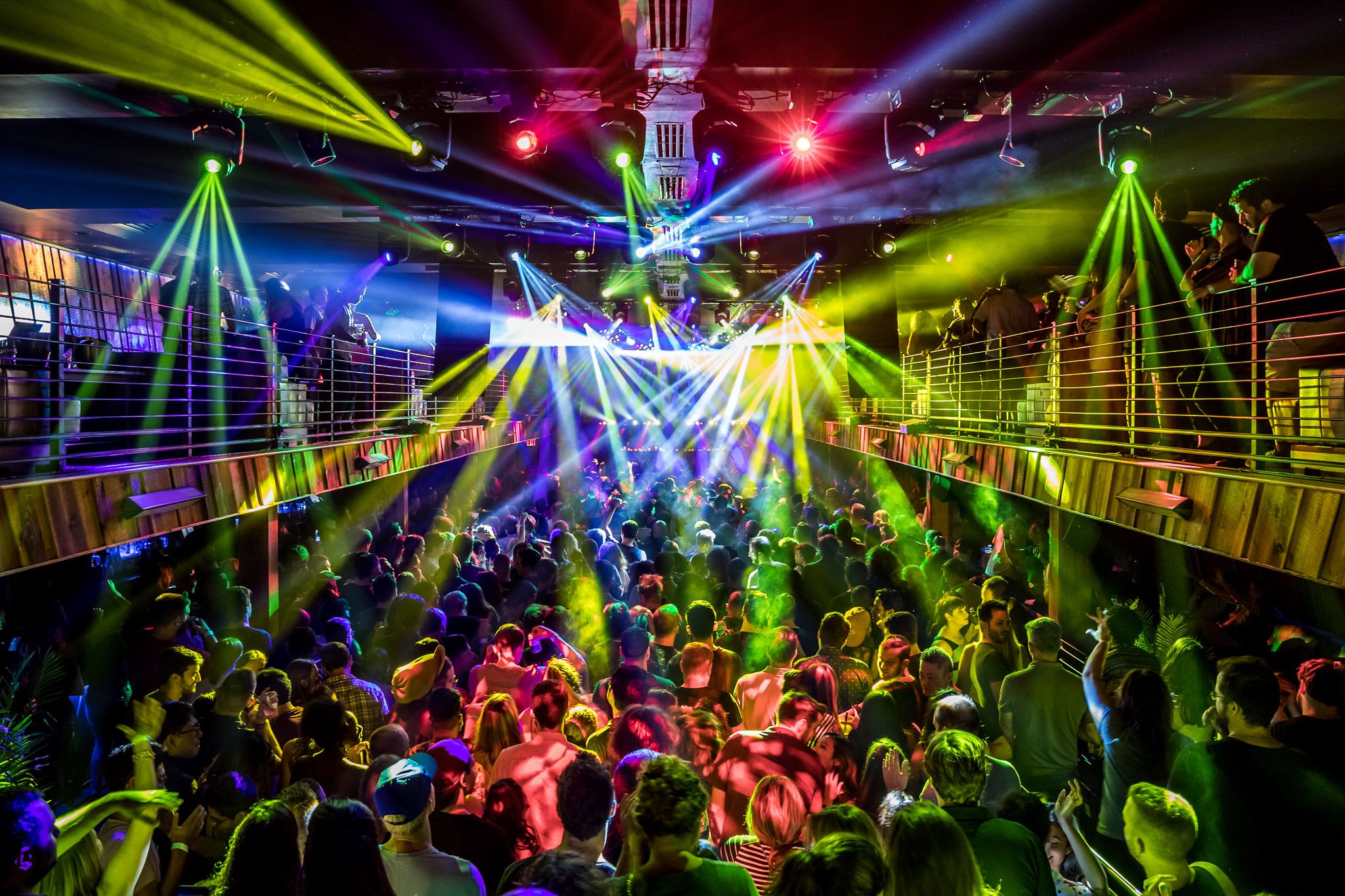 Wide BOH shot of the full production lights colored yellow, red, blue, and white illuminate the crowd on both the first floor and 2nd floor balconies.