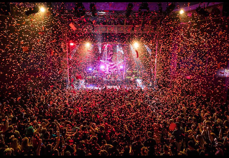 A large crowd gathered inside of Buckhead Theatre main room with red confetti falling onto the entire crowd and taking over the entire photo. 