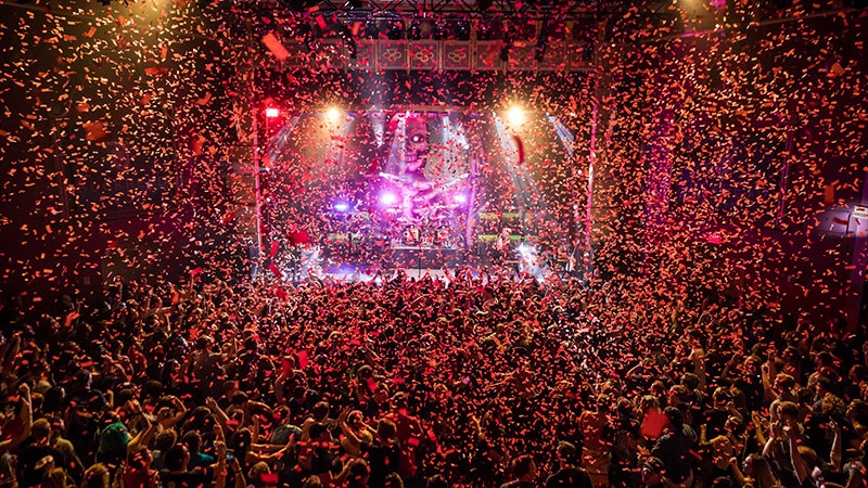 A large crowd gathered inside of Buckhead Theatre main room with red confetti falling onto the entire crowd and taking over the entire photo.