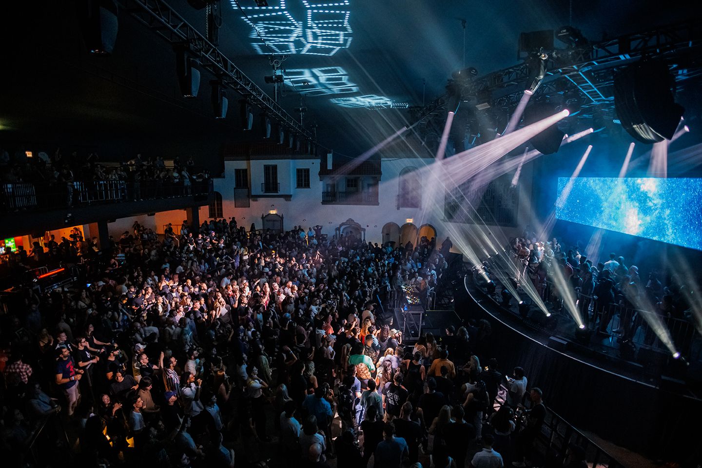Side stage view of Ramova Theatre stage from the Artist balcony with white lights shining and a top-view of the crowd