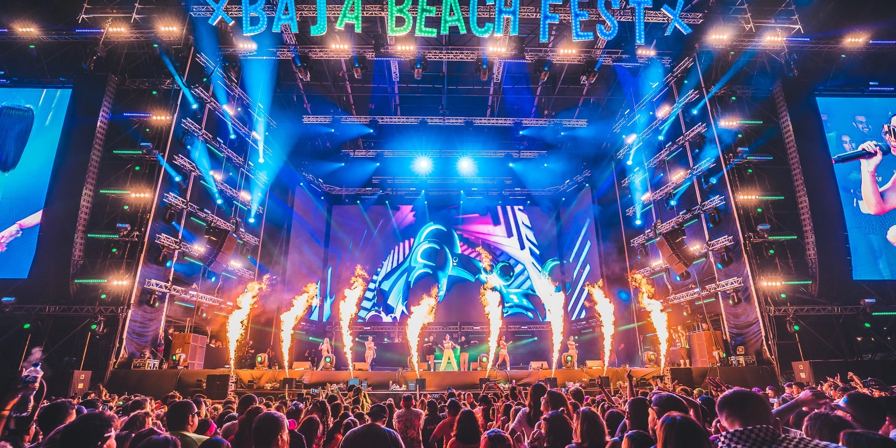 Photo of becky g at the mainstage of Baja Beach Fest with fire shooting in front of the stage with a packed crowd in front.