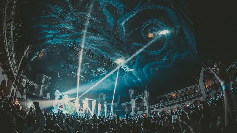 Wide shot of the Byline Bank Aragon Ballroom ceiling with abstract galaxy like painting. CO2 shoots off over a large packed crowd on the dance floor.