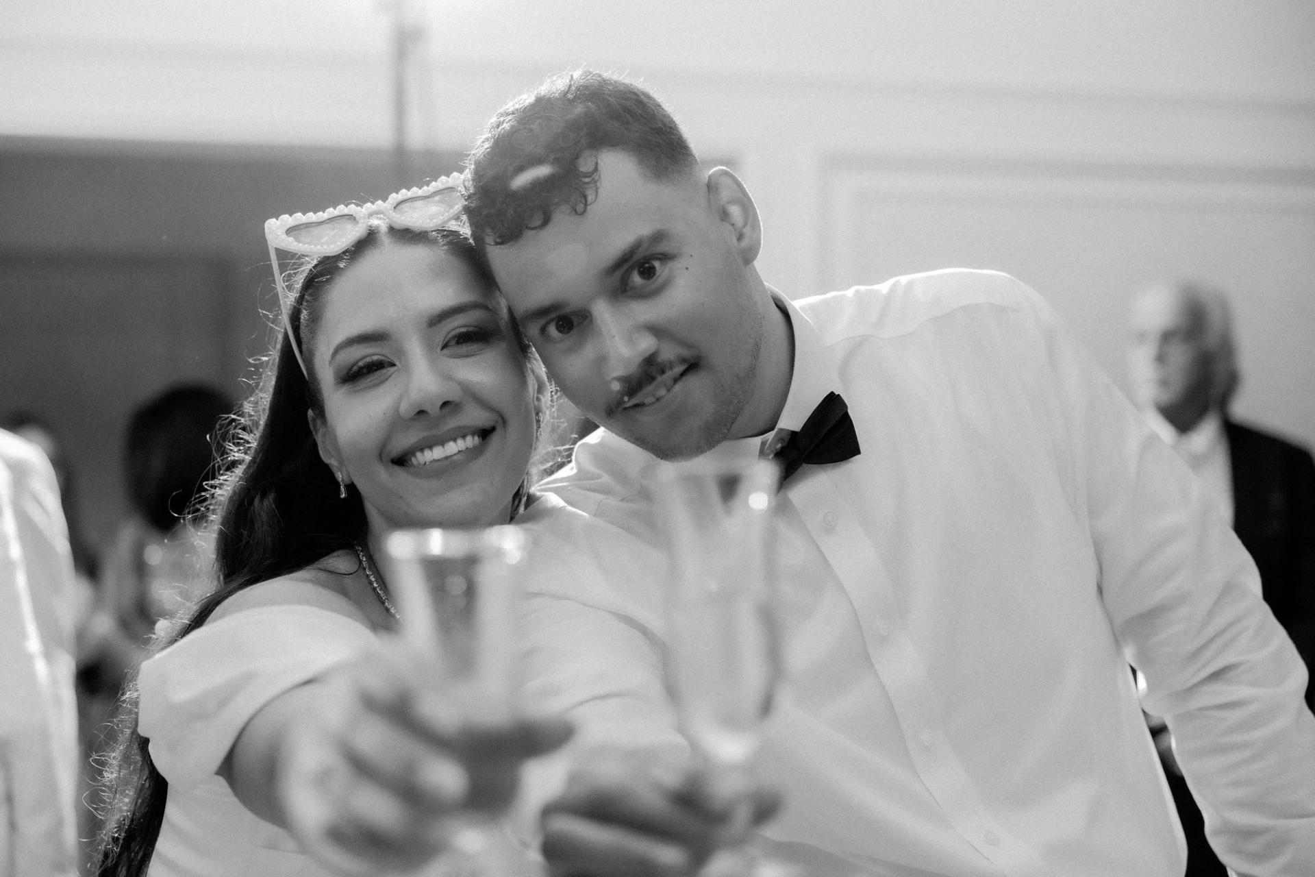 Les mariés portent un toast devant l’objectif en noir et blanc