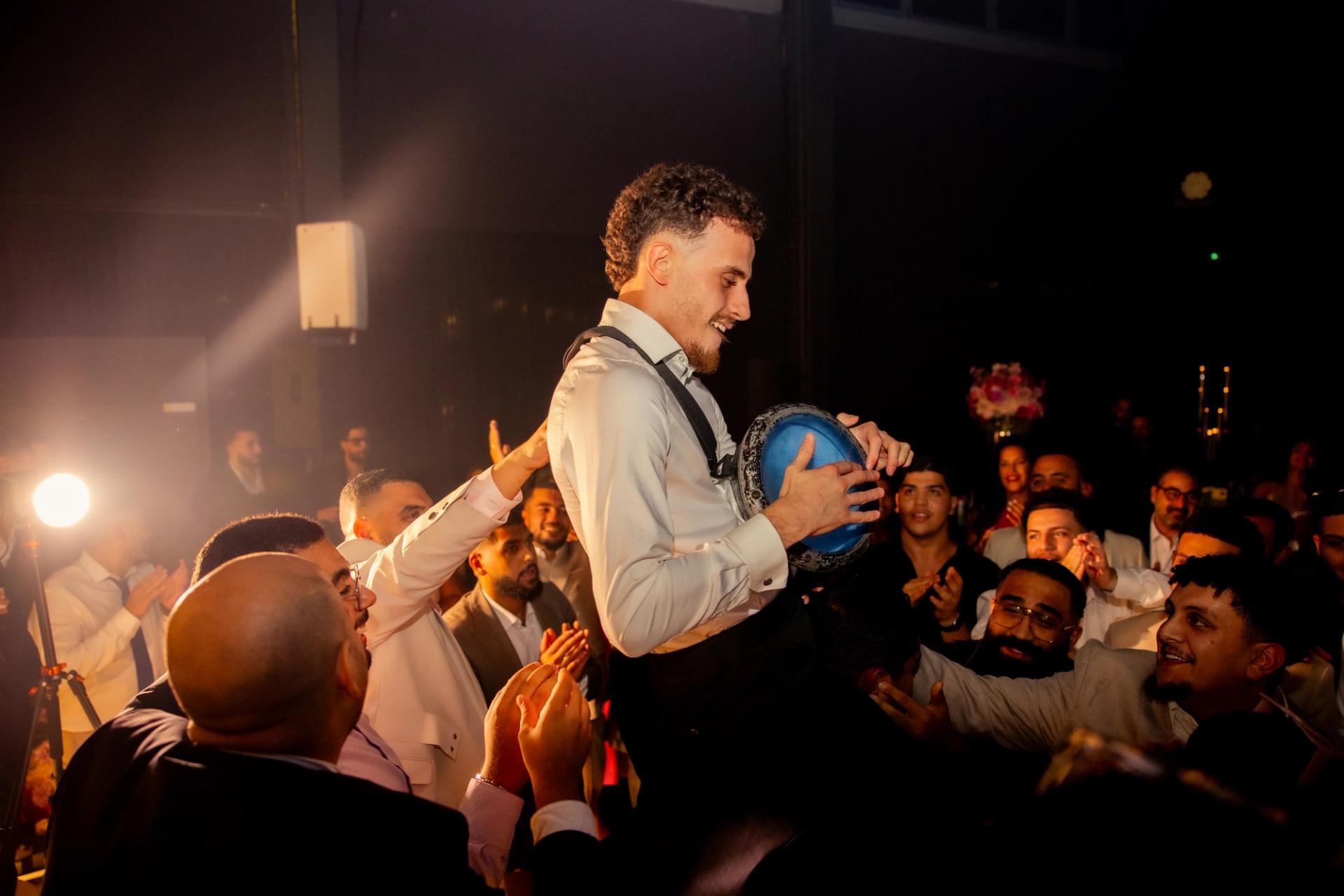 Un invité joue du tambourin porté par la foule