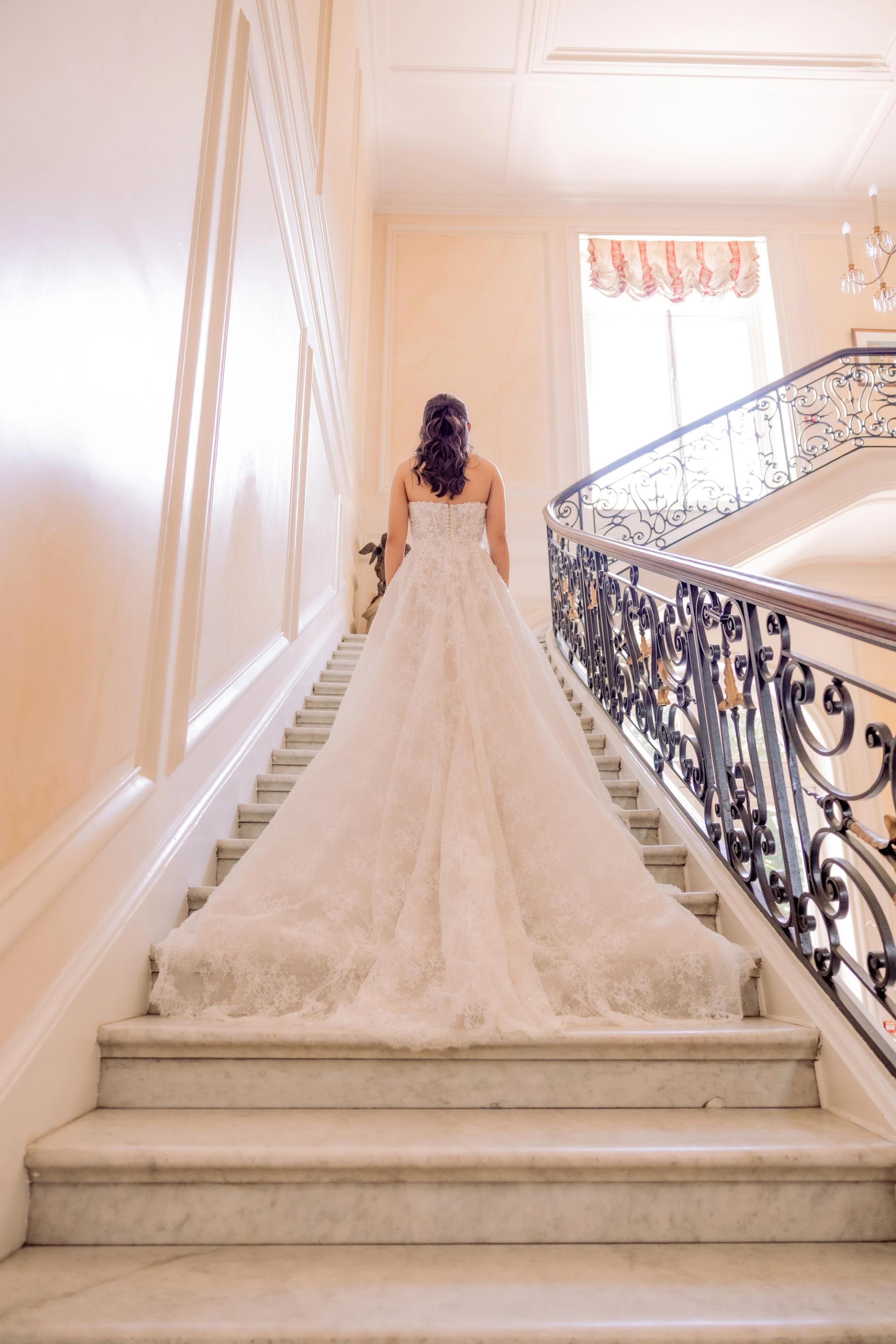 Anaïs descend l’escalier du château dans sa robe de mariée