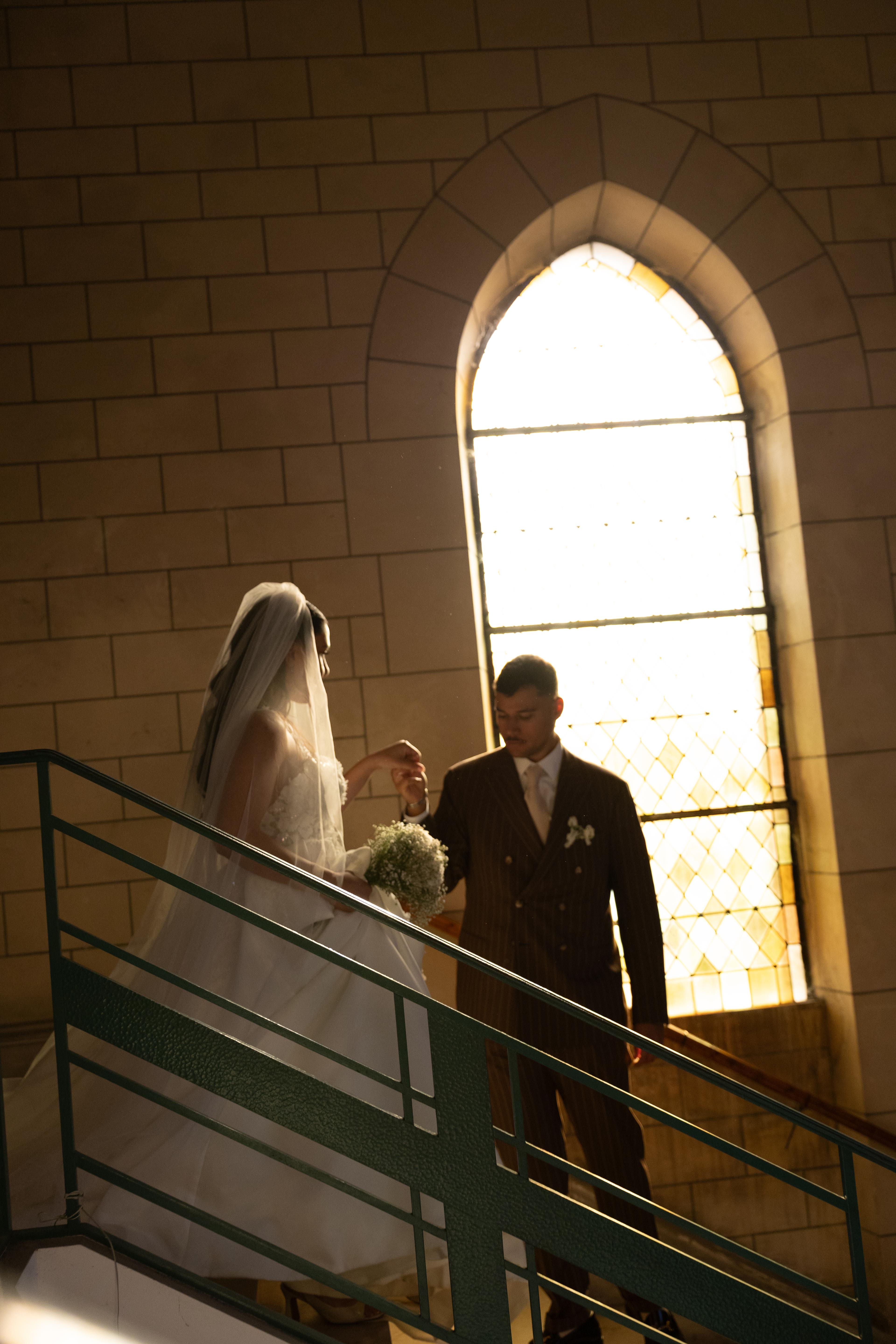 Silhouette des mariés devant un vitrail dans l’escalier
