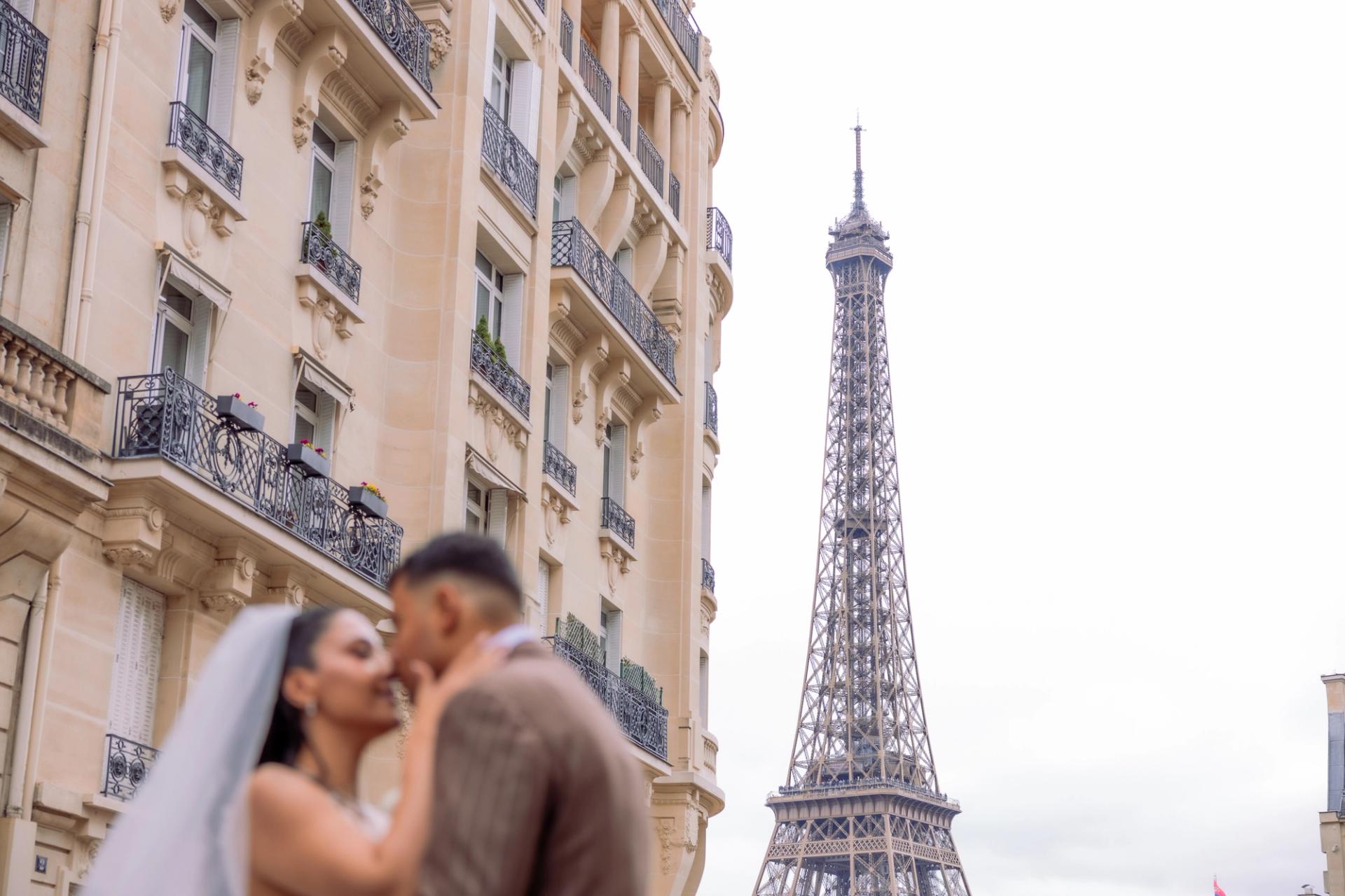 Baiser des mariés dans une rue avec la tour Eiffel