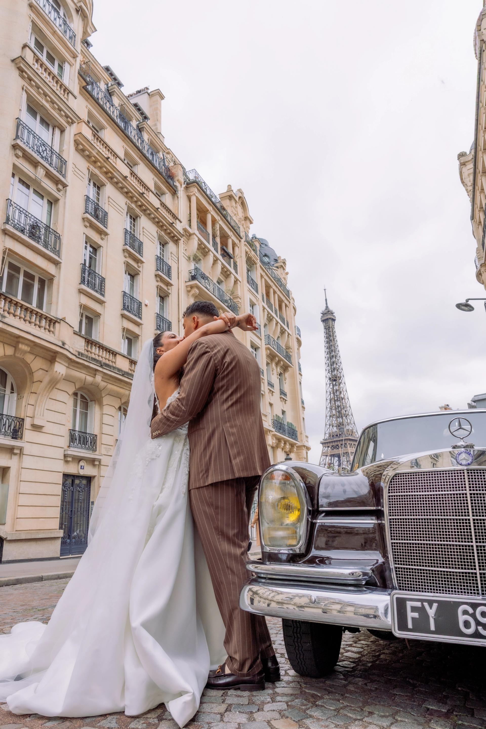 Baiser des mariés près de leur voiture ancienne