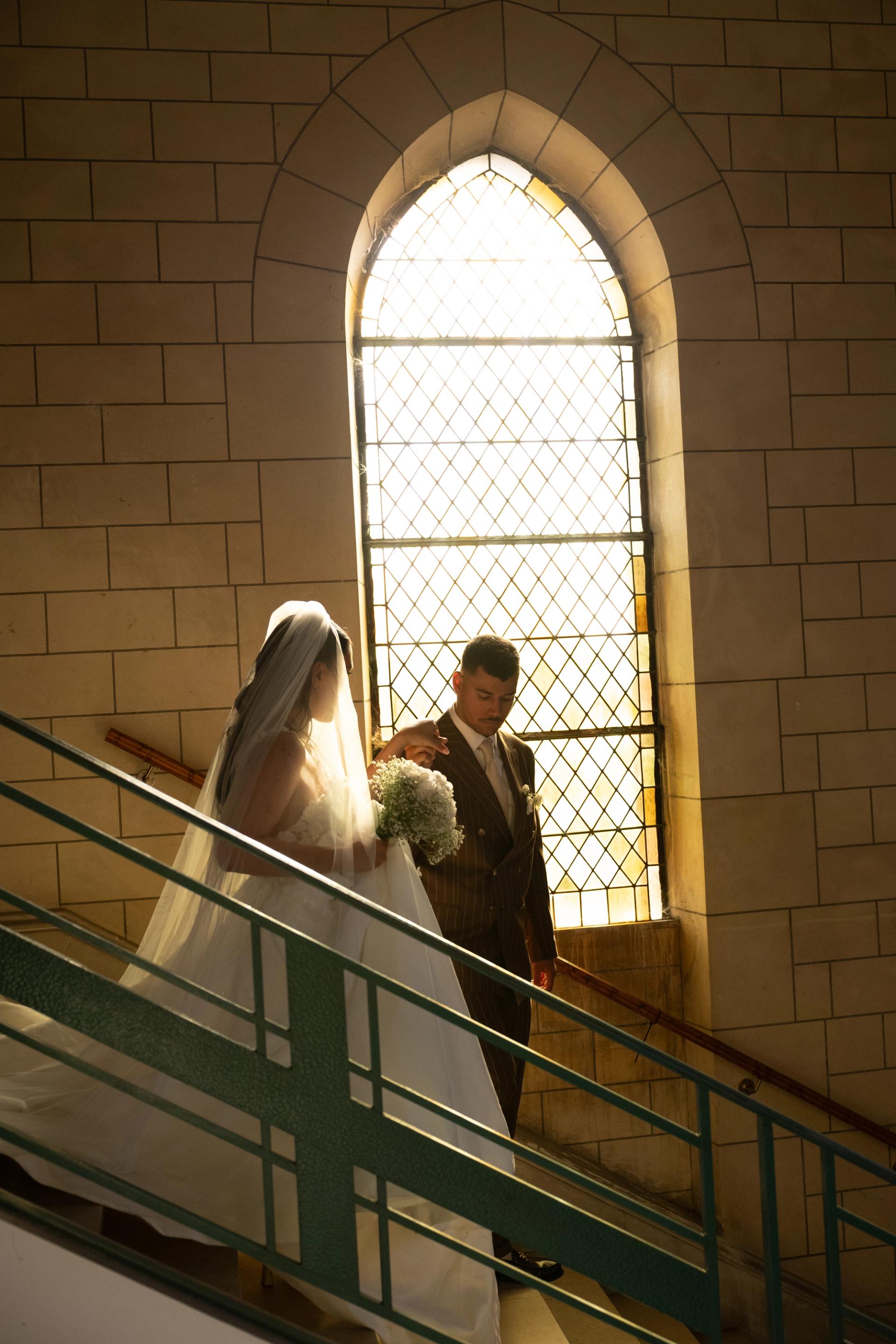 Silhouette des mariés dans l’escalier devant un vitrail