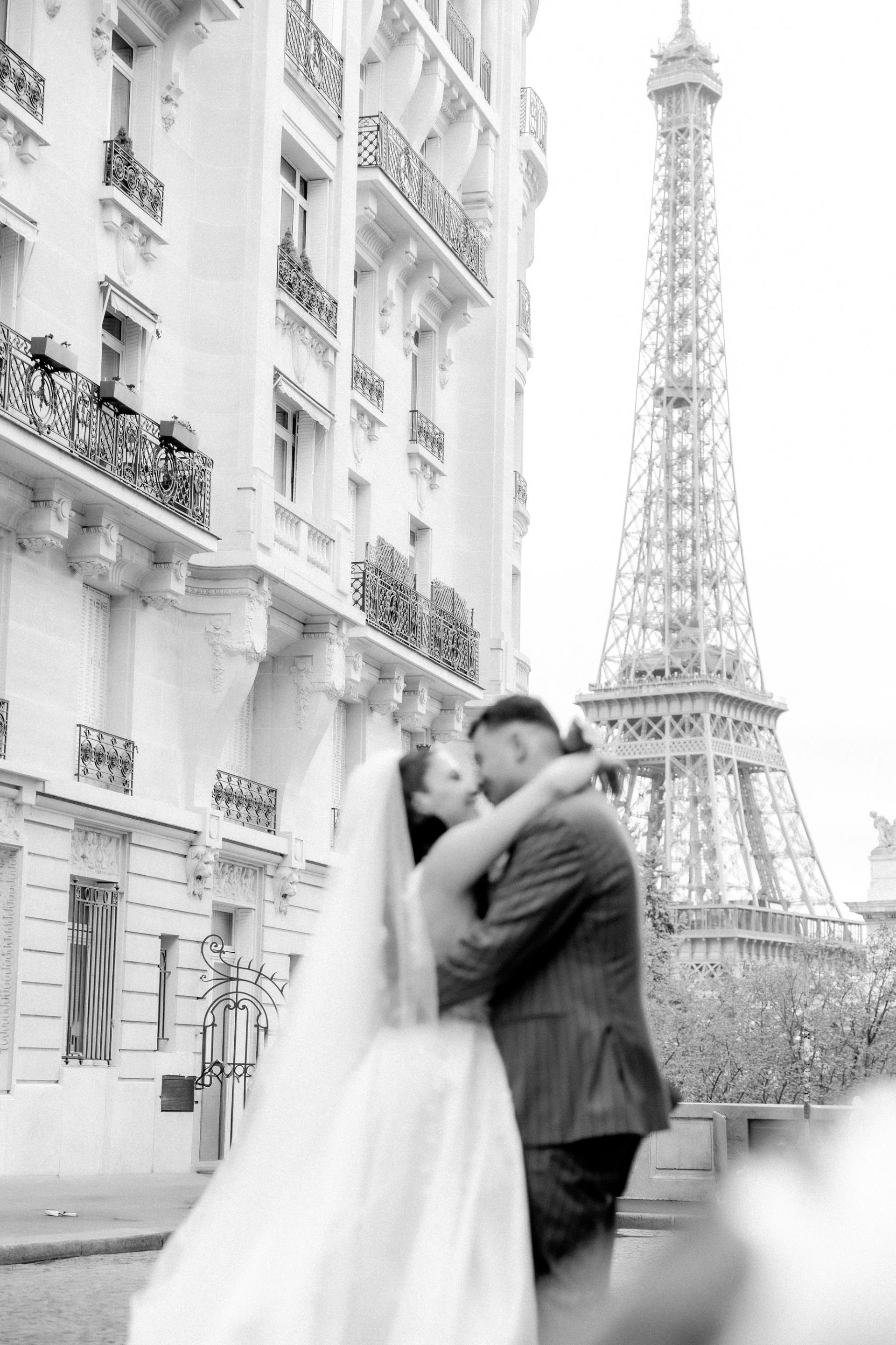 Marie Ange et William s’embrassent devant la tour Eiffel en noir et blanc
