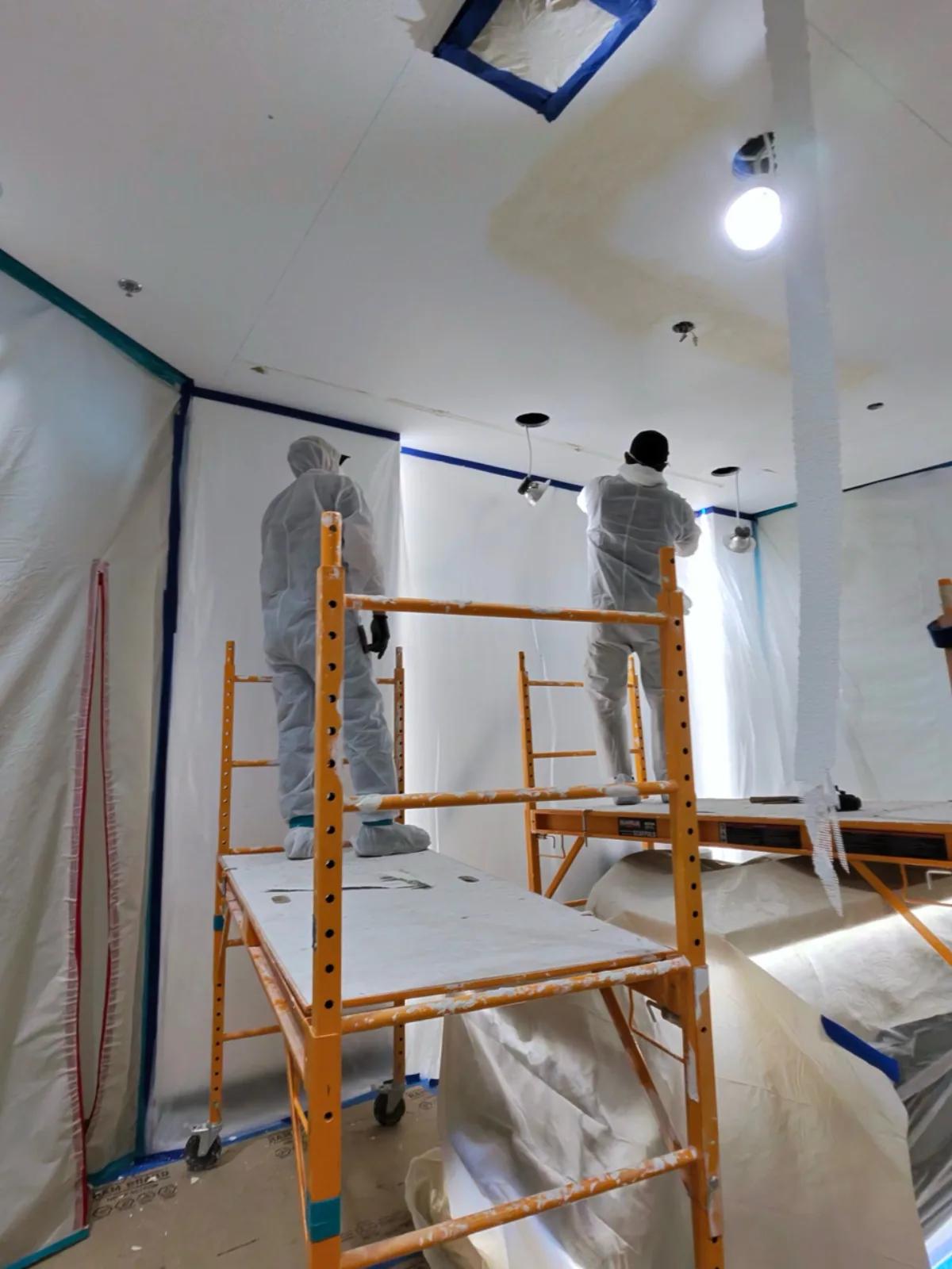 Quality 1st Restoration IICRC-certified crew in protective PPE working on scaffolding inside a fully contained workspace with plastic sheeting during a water damage ceiling restoration job in Henderson, NV