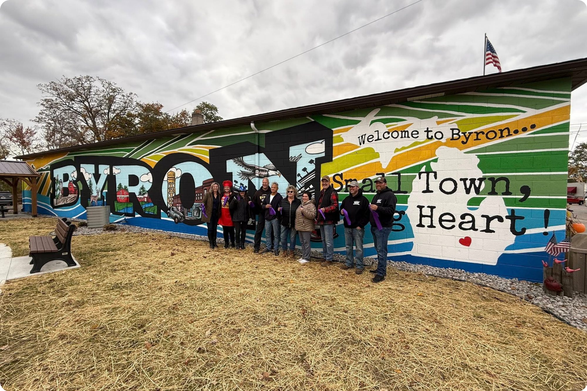 The Byron DDA poses before their new mural, which reads “Small Town, Big Heart!”