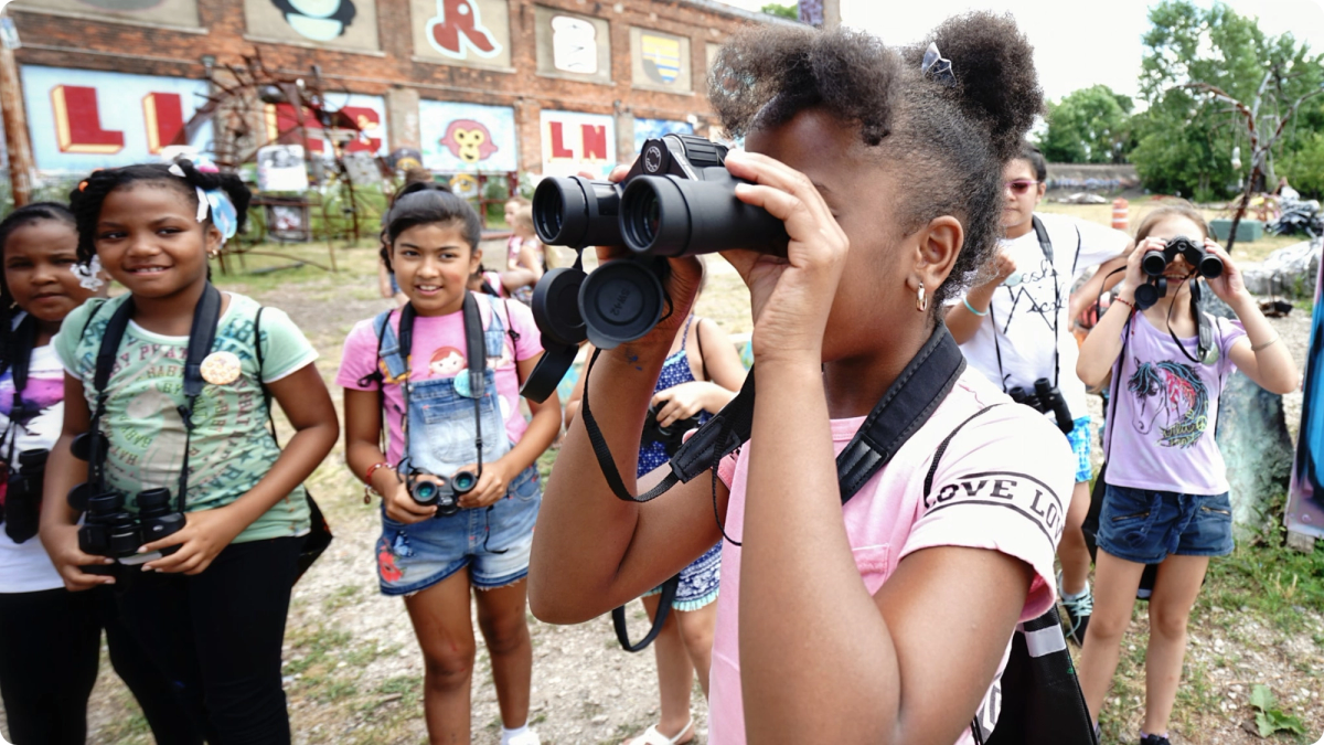 A group of young girls use binoculars at Lincoln Street Art Park and Activi-Tree Learning Center