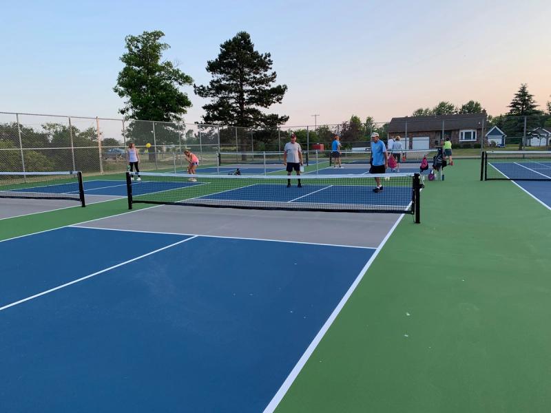 A pristine, new sports court with Pickleball players. 