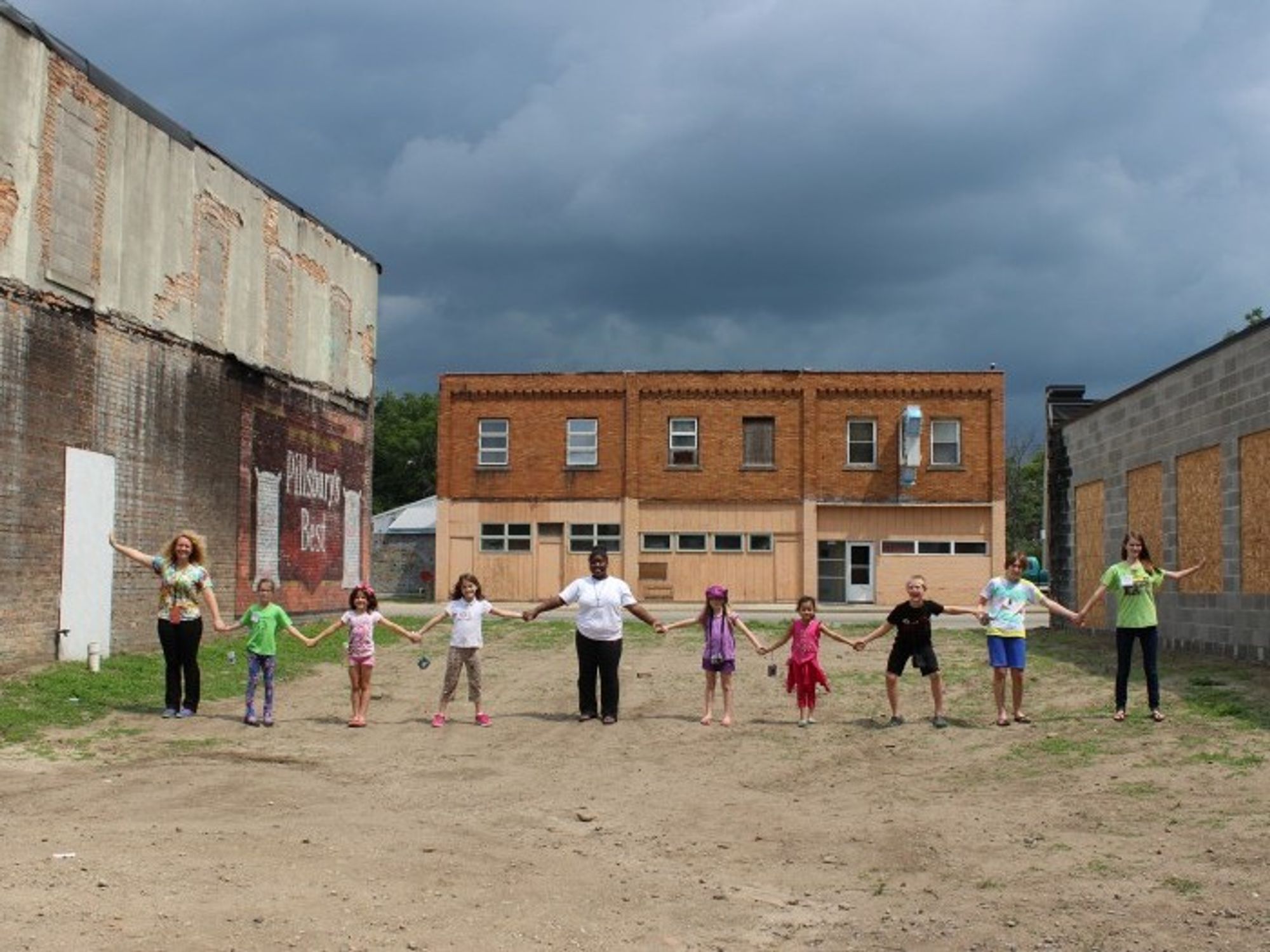 A group of children hold hands in a long line on the REACH organization campus in Lansing, Michigan.