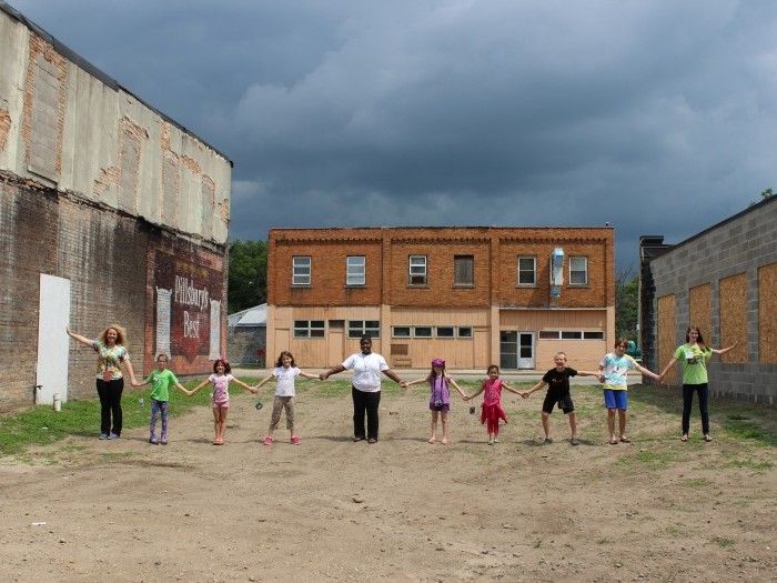 A group of children hold hands in a long line on the REACH organization campus in Lansing, Michigan.