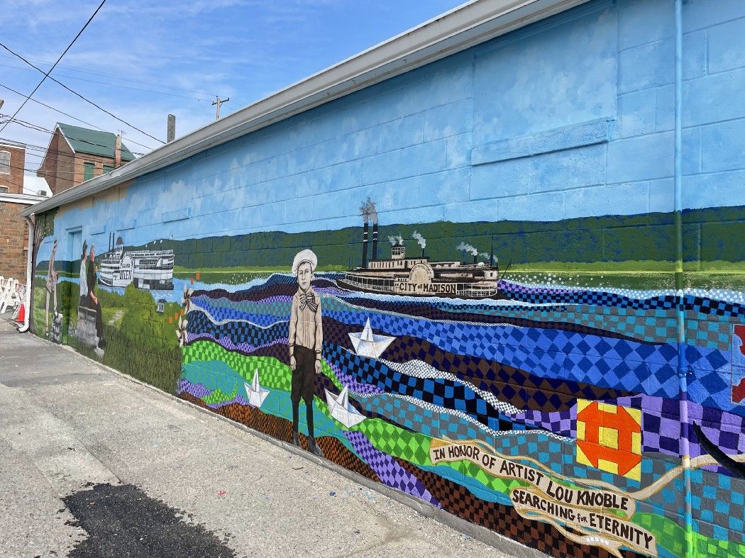 The colorful mural with a patchwork river, as if a quilt.