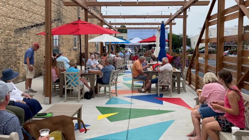 Bridgman Courtyard, a vibrant courtyard featuring a wooden pergola above public seating and a colorful, abstract ground mural. 