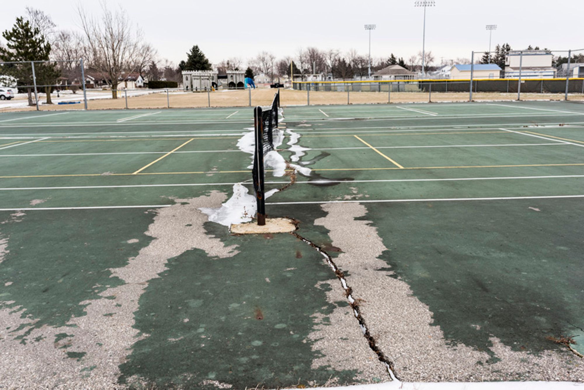 A before photo of the cracked and dirty tennis court. 