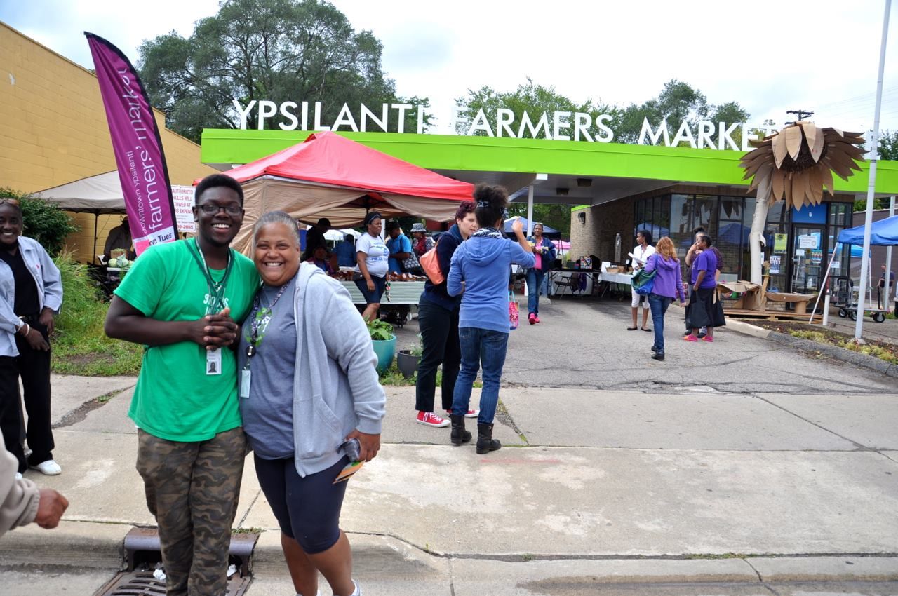 Ypsilanti Farmers MarketPlace with tents setup for market and people wandering through.
