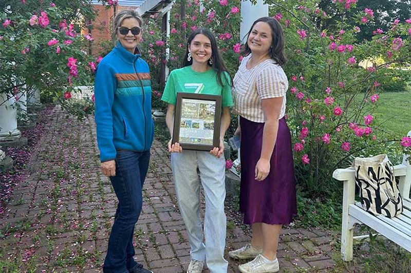 Paula Holtz and Mahala Clayton present an award to Sarah Hopkins.