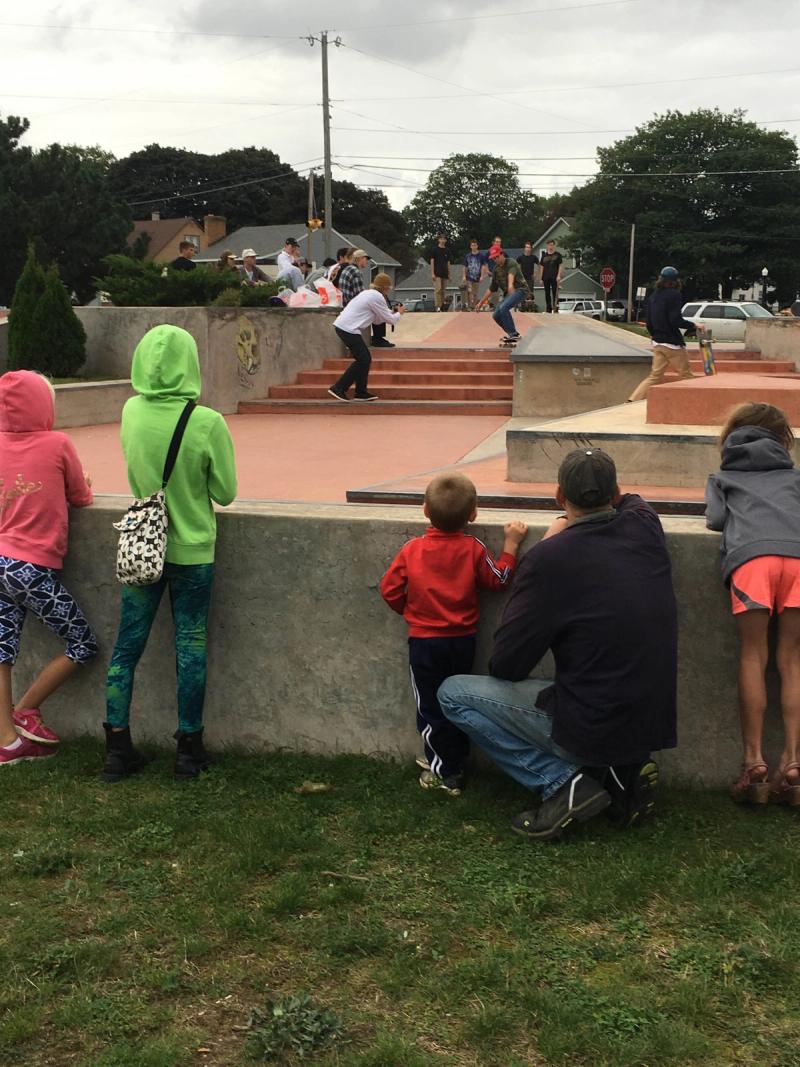 People enjoy the Marquette Skate Park. Kids watch in amazement over the outside wall.