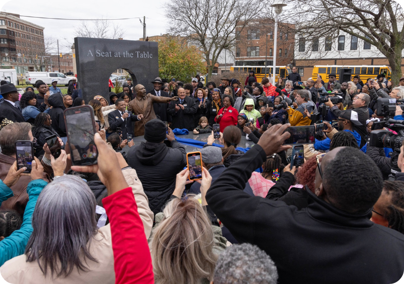 Community members record the opening ceremony at the new monument