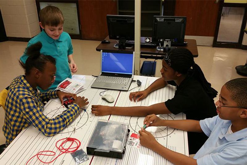 A group of elementary age children work together on a project at the makerspace.