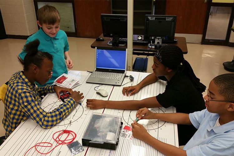 A group of elementary age children work together on a project at the makerspace.