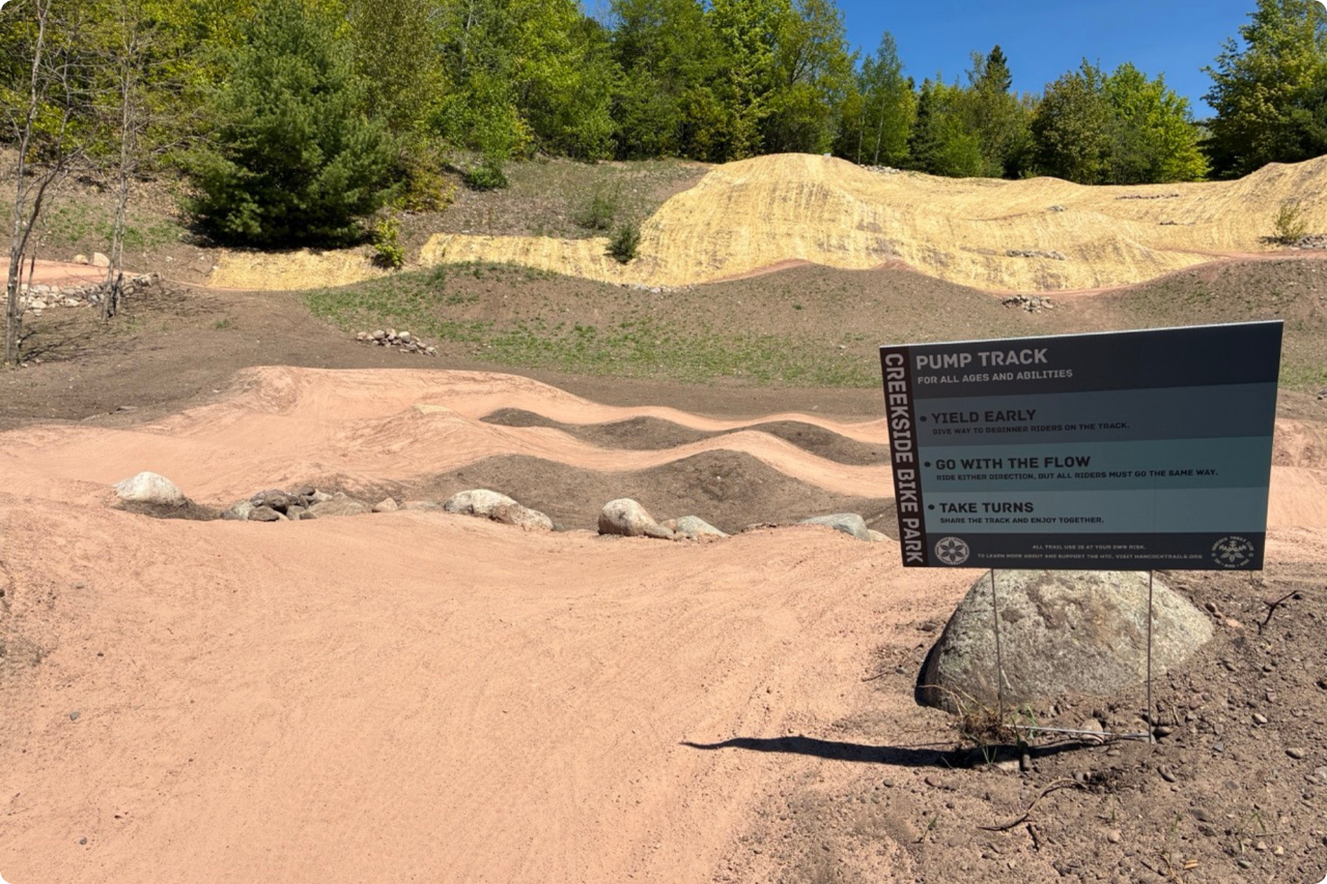 A sign at the start of the pump track, a more accessible mountain bike path for beginners.