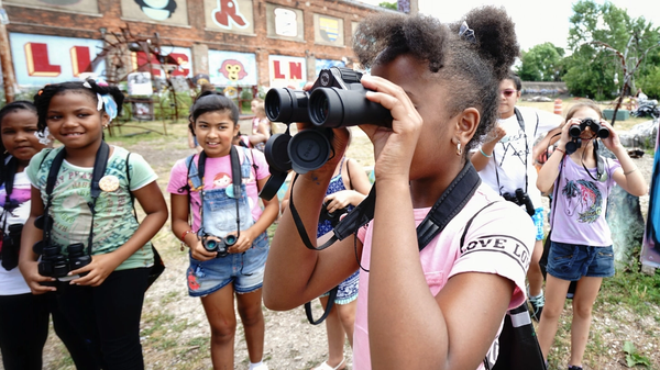 A group of young girls use binoculars at Lincoln Street Art Park and Activi-Tree Learning Center