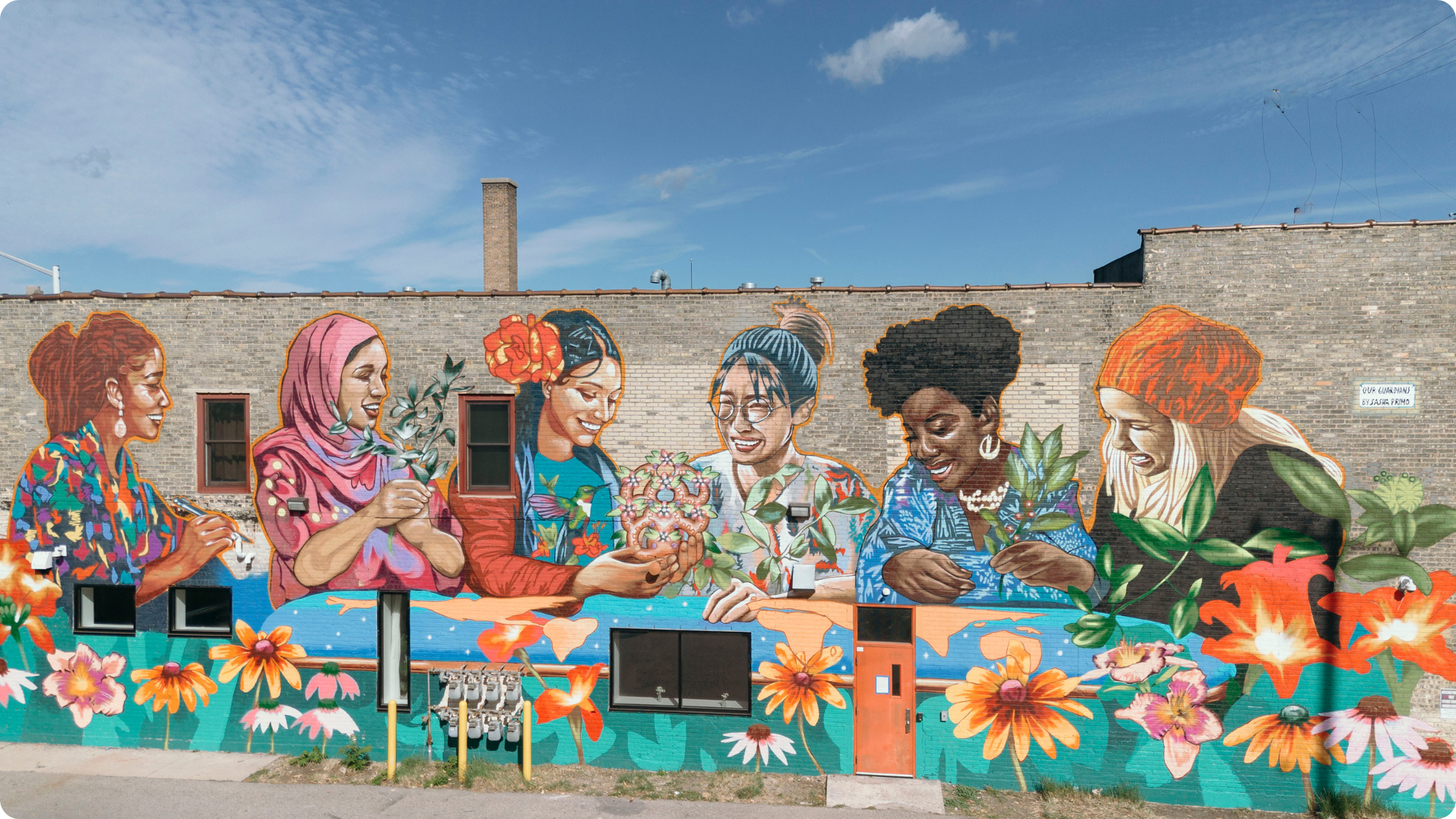 A vibrant mural of women on a brick building.