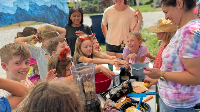 A group of elementary school students stand around a table for a cooking workshop at the farm.