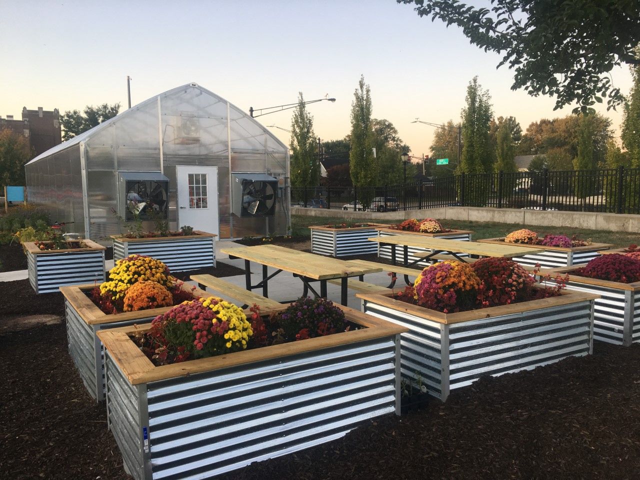The Community Education Greenhouse has picnic tables and raised beds by the entrance for outdoor learning.