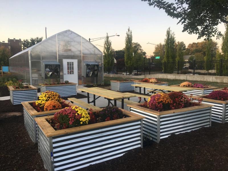 The Community Education Greenhouse has picnic tables and raised beds by the entrance for outdoor learning.
