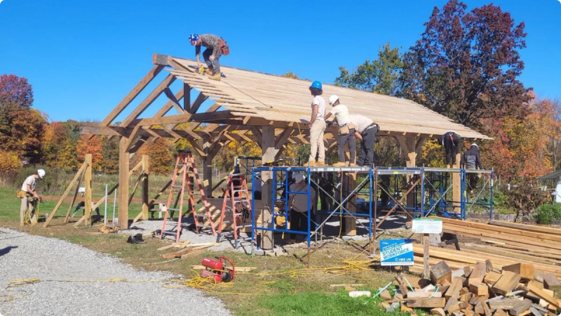  A construction crew of local high school students installs the roof wood boards of the Massaro Community Farm solar pavilion.